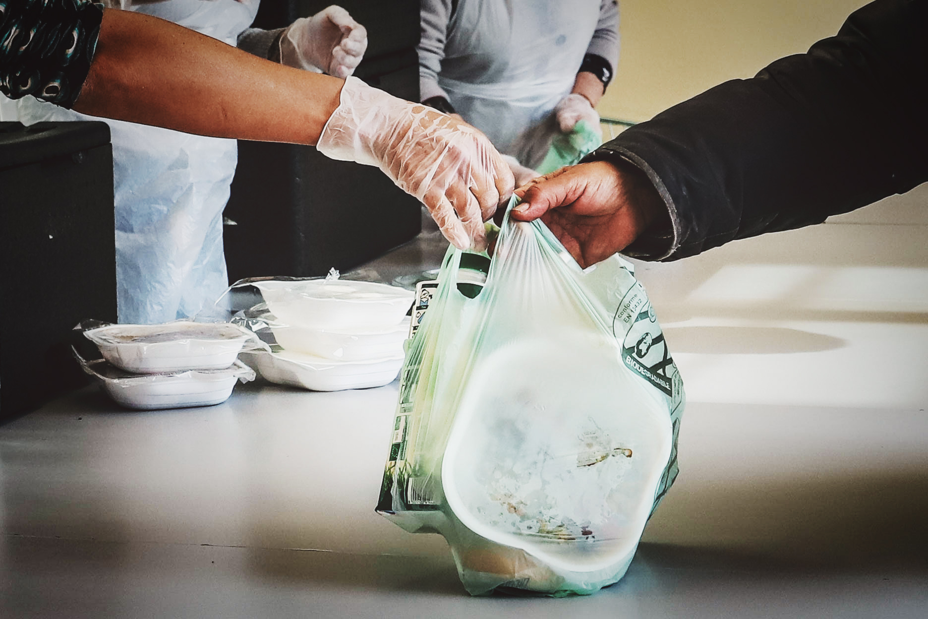 Due mani che si scambiano un sacchetto contenente generi alimentari di prima necessità